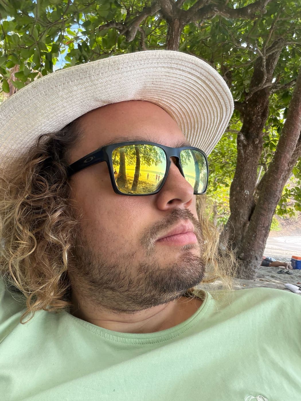 Jose in a straw hat and sunglasses in the shade at the beach