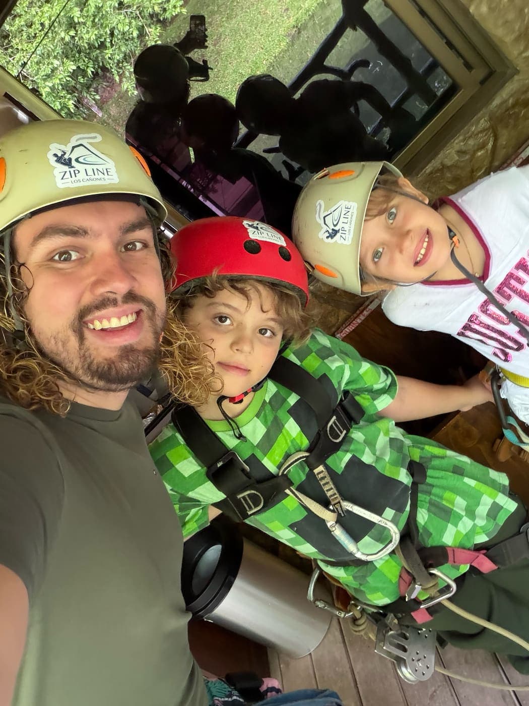Jose and his two children in helmets and climbing harnesses before a zip line run