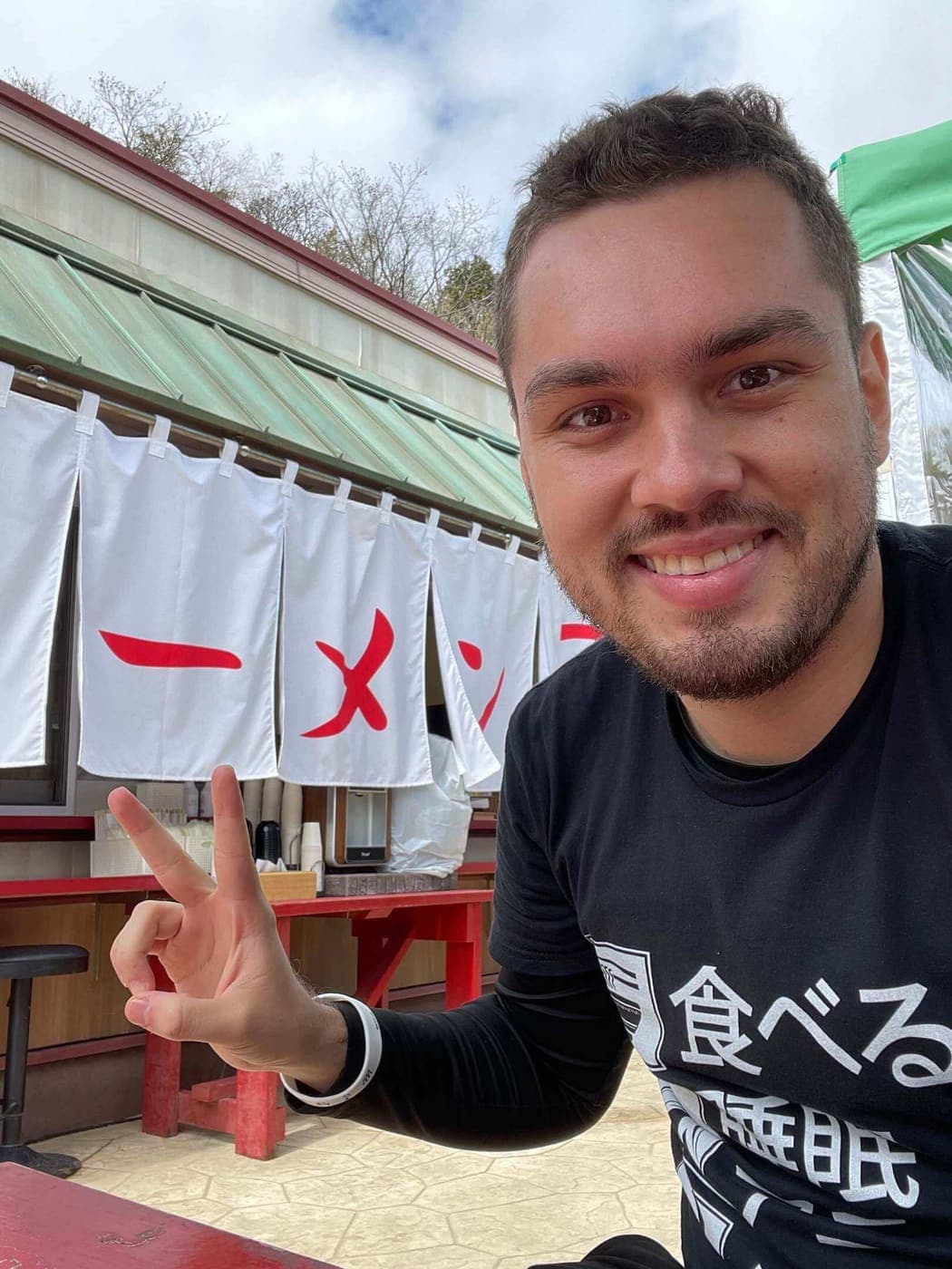 Jose outside a ramen shop in Japan, under the noren curtains